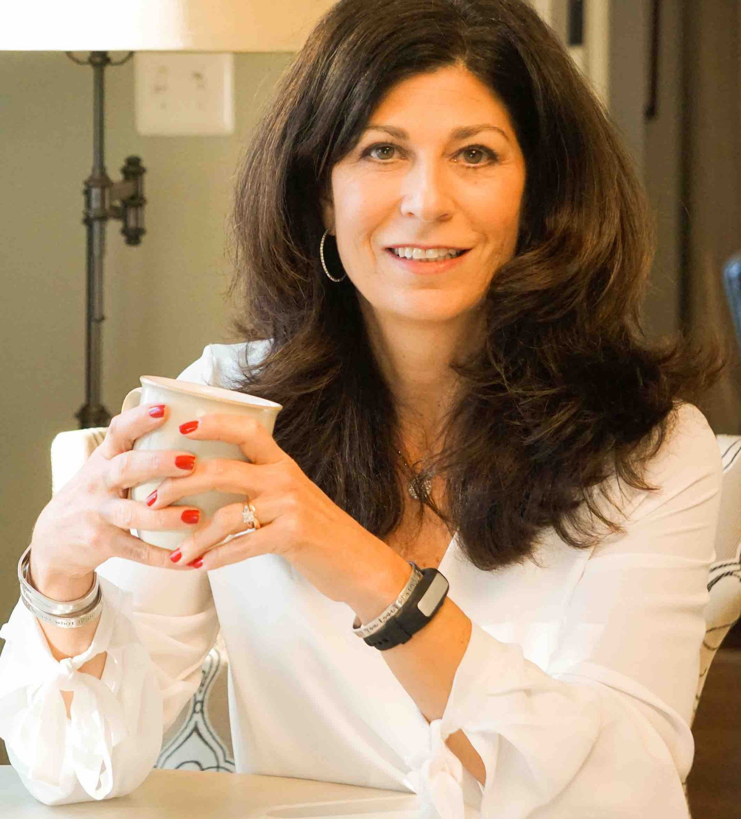 A woman sitting at a table with a cup of coffee.