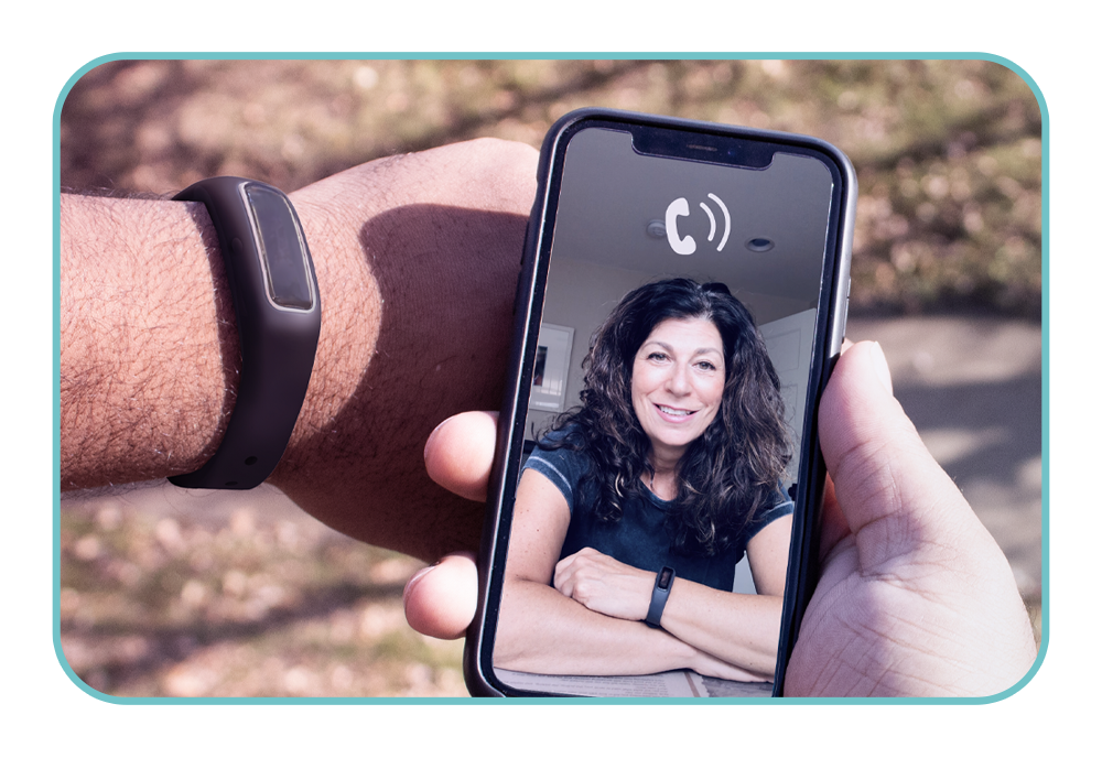 A person holding a smart phone with a person on the screen.