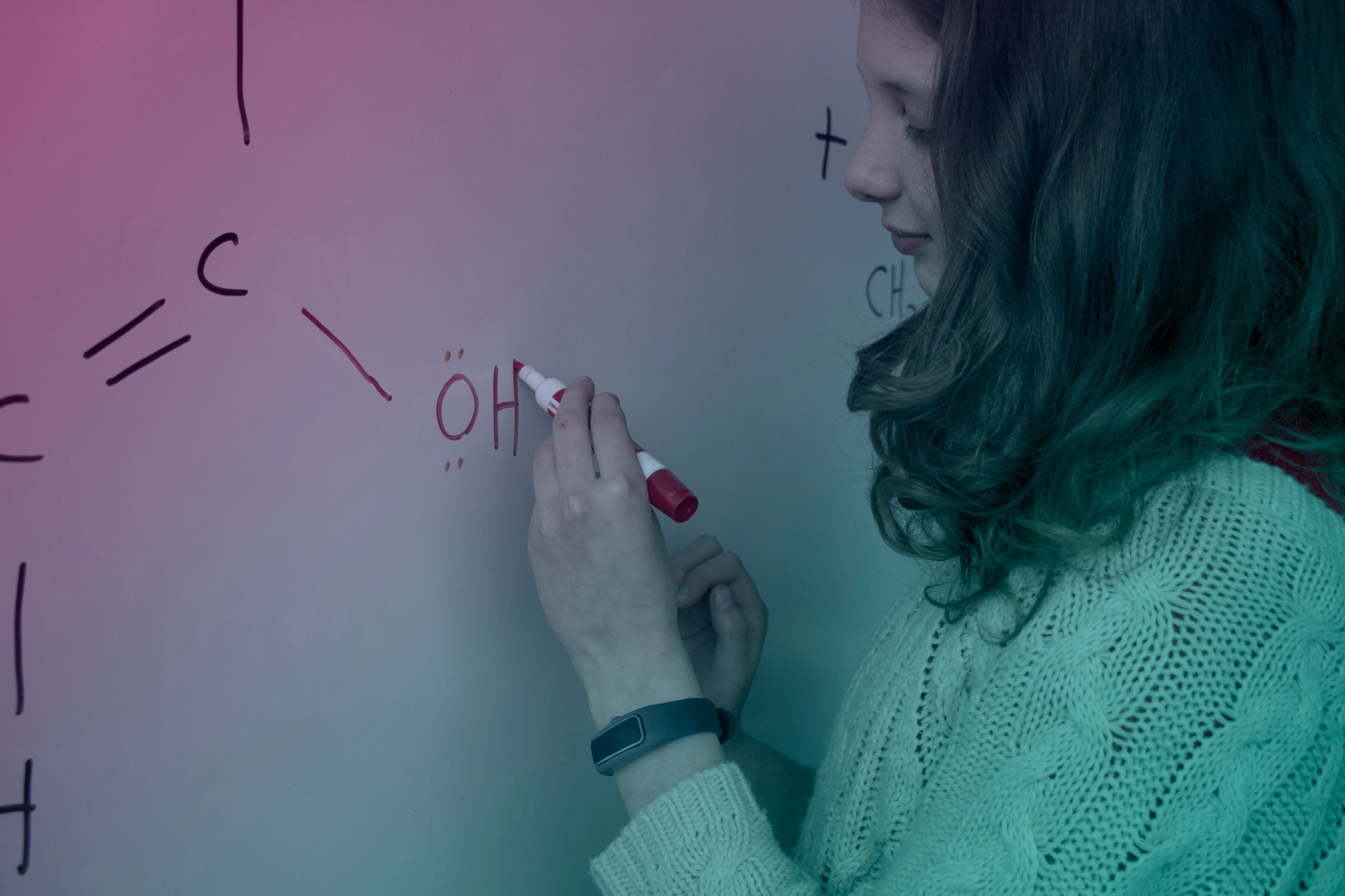 A girl writing on a whiteboard with a marker.