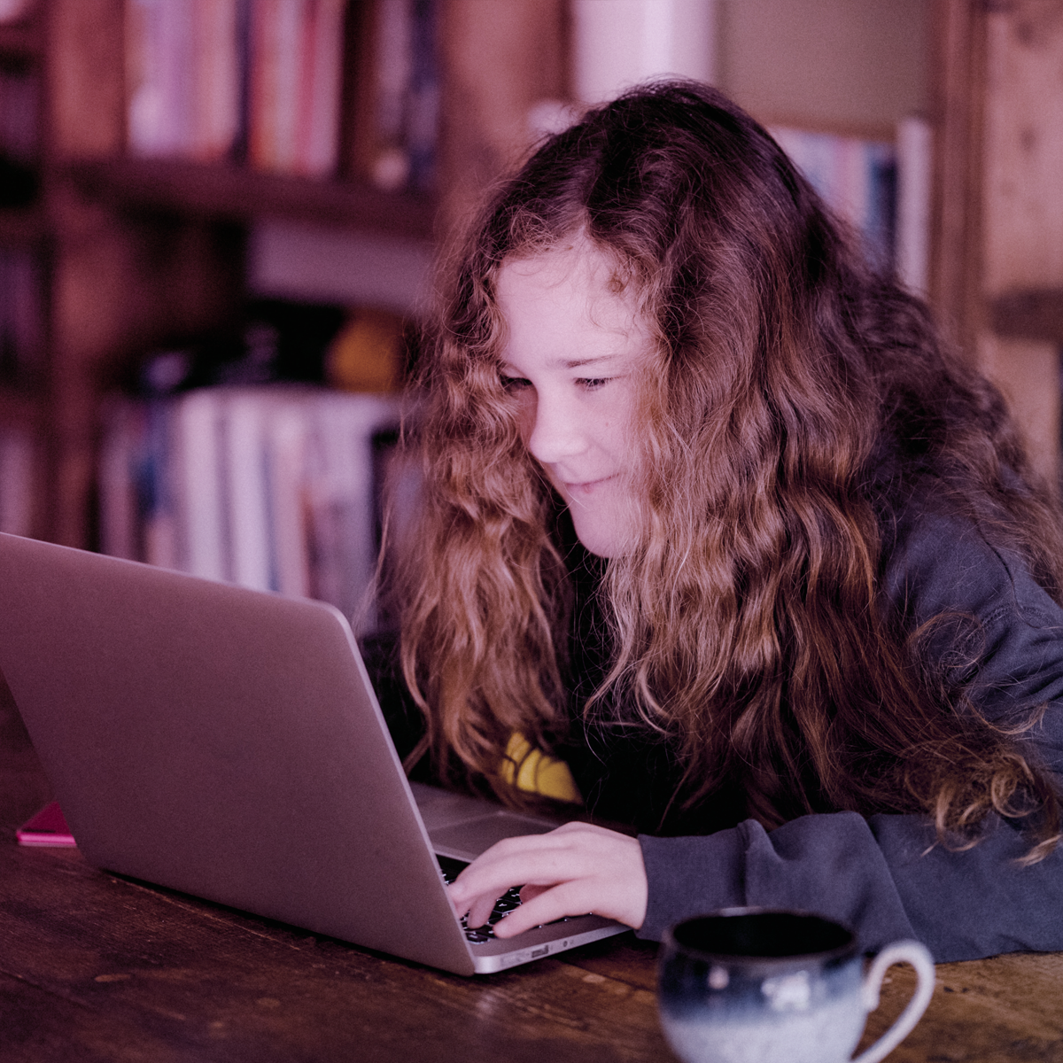 A girl sitting at a table with a laptop.